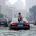 Las inundaciones en Tianjin, China, han provocado este tipo de imágenes: un hombre sentado en el techo del coche al no poder seguir avanzando.