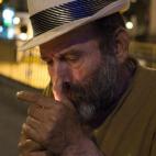 Papi se enciende un cigarro mientras cuenta que cuando la gente sale de fiesta, suelen aliviar sus necesidades al lado de donde él duerme