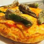 ¿Qué convierte a esta tortilla en gallega? El queso de tetilla, el pimentón, el lacón y los pimientos del padrón que incorpora. Éste es el paso a paso para hacerla.