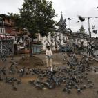 Un hombre da de comer a las palomas durante el toque de queda en el centro de Srinagar, India.