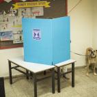 Una electora de Tel Aviv, con su perro tras el cartón que sirve de cortina en los colegios de Israel.