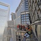 Un grupo de personas caminando por la pasarela acristalada de la Torre Jinmao en Shanghái (China). Los turistas pueden pasear por ella ayudados de cuerdas de seguridad.