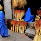 Compradoras afganas miran una tienda de escobas de Herat.