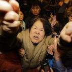 Un familiar de uno de los pasajeros chinos del vuelo de Malaysia Airlines MH370 grita a los periodistas tras conocerse que el avión terminó su recorrido en el Índico sur.