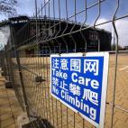 Una valla rodea el campo de voley playa abandonado.