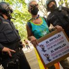 Mujer con una pancarta y una bandera al lado de los polic&iacute;as en la concentraci&oacute;n contra S&aacute;nchez en el Liceo.