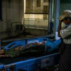 Un hombre llora al pie de la camilla de uno de los muertos.