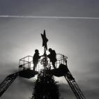 Trabajadores decoran un árbol de Navidad en Lenin's Square en Stavropol (Rusia) mientras pasa un avión.
