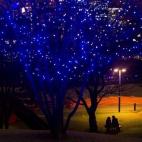 Una pareja se sienta bajo las luces en un parque en el centro de Tokio, Japón.