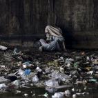 Un drogodependiente afgano se cubre la cabeza con una bufanda bajo un puente en Kabul, Afganistán.