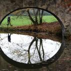 Una mujer se refleja en el agua bajo un puente del parque Hanau-Wilhelmsbad, en Frankfurt am Main (Alemania).