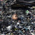 Un niño, entre los desechos que ha dejado el gran incendio que ha arrasado más de 200 casas en la comunidad de Tonsuya, al norte de Manila (Filipinas).