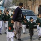 Un trabajador de seguridad acompaña a los estudiantes rescatados de una escuela cercana a la del ataque. (AP Photo/Mohammad Sajjad)