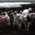 Voluntarios realizando una cadena humana para transportar los capachos con chapapote en Muxía.