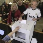 Un ciudadano, vestido con la camiseta del Real Madrid, deposita su papeleta, en el Institut Montserrat de Barcelona.