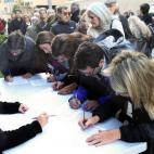 Varios ciudadanos que esperan la cola para depositar su papeleta en el colegio situado en el polideportivo la Salle de Barcelona firman el manifiesto que pide a las autoridades europeas el derecho a decidir.