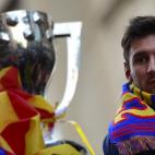 Barcelona's Argentinian forward Lionel Messi looks at the cup as he and his teammates parade on a bus through a crowd of supporters celebrating in the streets of Barcelona on May 13, 2013, two days after their team won the Spanish league. The Ca...