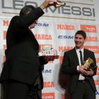 Barcelona's Argentinian forward Lionel Messi (R) poses after receiving the European Golden Boot 2012 award for best European goalscorer of the 2011-2012 season next to Oscar Campillo, director of the Marca sports newspaper, on October 29, 2012 i...