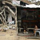 Varios palestinos se calientan alrededor de un pequeño fuego en un rudimentario refugio fabricado al lado de los restos de su casa, que fue destruida en un bombardeo israelí el pasado verano en Gaza.