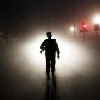 La silueta de un agente de seguridad ante las luces de un coche, mientras hace guardia antes del Día Anual de la República, en una nublada mañana de invierno en Nueva Delhi, India.