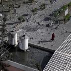 Una mujer camina por una calle de Gaza llena de restos de los bombardeos.