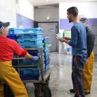 Tras terminar su jornada en el mar, los pescadores descargan su mercanc&iacute;a en la lonja.