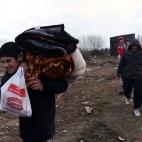 CALAIS, FRANCE - FEBRUARY 29: Migrants carry their possessions as they leave their tents as police officers clear part of the 'jungle' migrant camp on February 29, 2016 in Calais, France The French authorities have begun dismantling part of th...