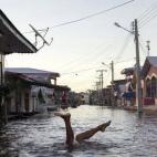 Un niño juega en una calle inundada por el río Solimoes, uno de los afluentes principales del Amazonas, en Anama, Brasil.