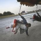 En Kabul hay feriantes que, en medio de la nada, despliegan caballitos para dar vueltas sobre el mundo. Los niños alargan la mano para acariciar el planeta Tierra. Al fondo de la foto, casi imperceptibles, un montón de drogadictos. La policí...