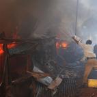 Un grupo de kenianos tratan de apagar un fuego con cubos de agua causado por un fallo eléctrico en una de las viviendas del poblado Deep Sea de los suburbios de Nairobi.