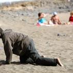 Un inmigrante llega en patera a una playa de Fuerteventura mientras unos turistas toman el sol en mayo de 2006.