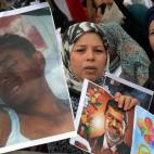 Una mujer muestra, en una marcha en favor de Morsi en París, una fotografía del depuesto presidente egipcio y otra de un hombre herido durante los enfrentamientos del día de la ira.