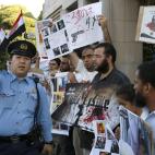 Un agente japonés trata de controlar la protesta de egipcios residentes en Japón a favor de Morsi frente a la embajada de Egipto en Tokio.
