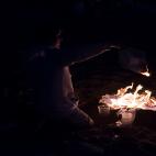 Un joven quema apuntes en una hoguera en la playa de Santander