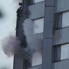 Un residente del edificio saca un brazo que agita una toalla, pidiendo auxilio.