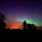 El color de un incendio forestal brilla bajo las auroras boreales en Alberta, Canadá.