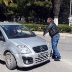 Un policía de paisano para a un vehículo en la zona que están acordonando las fuerzas de seguridad.