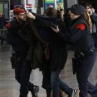 Dos agentes ayudan a cubrirse y avanzar a una mujer con seres queridos en el vuelo.