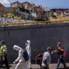 Una brigada de fumigación y desinfección trabajando en la calle principal de la zona de Petare.