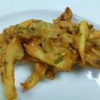 Patatas fritas con cebolla envueltas en harina de garbanzos y harina normal con especias para aromatizar. Puedes ver la receta completa aquí