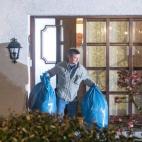 Un Policía saca bolsas de la casa.