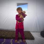 En esta foto del miércoles 7 de noviembre de 2012, Amina Al Sado, de 5 años, posa dentro de una carpa para desplazados, cerca de la frontera entre Siria y Turquía, luego de huir con su familia desde su comunidad (AP Foto/Khalil Hamra)