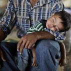 Ghassan Khalil, de 30 años, que se escapó de su pueblo Marea, Siria hace 12 días a causa del cañoneo de las tropas del gobierno a su casa, sostiene a su hijo dormido de dos años de edad. que tiene fiebre. Ellos integran un grupo de sirios q...