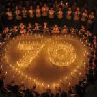 Estudiantes de una escuela de primaria se reúnen alrededor de un número 70 formado por candelabros durante un memorial para recordar a los mártires de la II Guerra Mundial, en Shangrao (China).