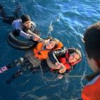 La Guardia Costera turca ayuda a los refugiados con salvavidas, después de que volcara el bote en el que iban hacia Grecia.