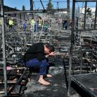 Un hombre se sujeta la cabeza con las manos, sentado entre estructuras de camas quemadas por un incendio en un campo de refugiados en Diavata, al norte de Grecia, el 20 de abril. Se destruyeron más de una docena de tiendas, poniendo en peligro ...