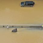 Un coche y una motocicleta tratan de avanzar por una calle inundada tras el paso del Tifón Meranti el 15 de septiembre en Fuzhou, en la provincia de Fujian (China).