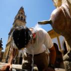 Un turista se refresca en una de las fuentes del Patio de los Naranjos de la Mezquita catedral de C&oacute;rdoba.