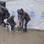 Varios refugiados se calientan junto a una hoguera bajo la nieve en el campamento de refugiados de Moria, en la isla de Lesbos, Grecia.