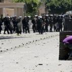 Un joven se parapeta tras un bidón durante los enfrentamientos contra los antidisturbios frente al Ministerio del Interior egipcio en El Cairo.